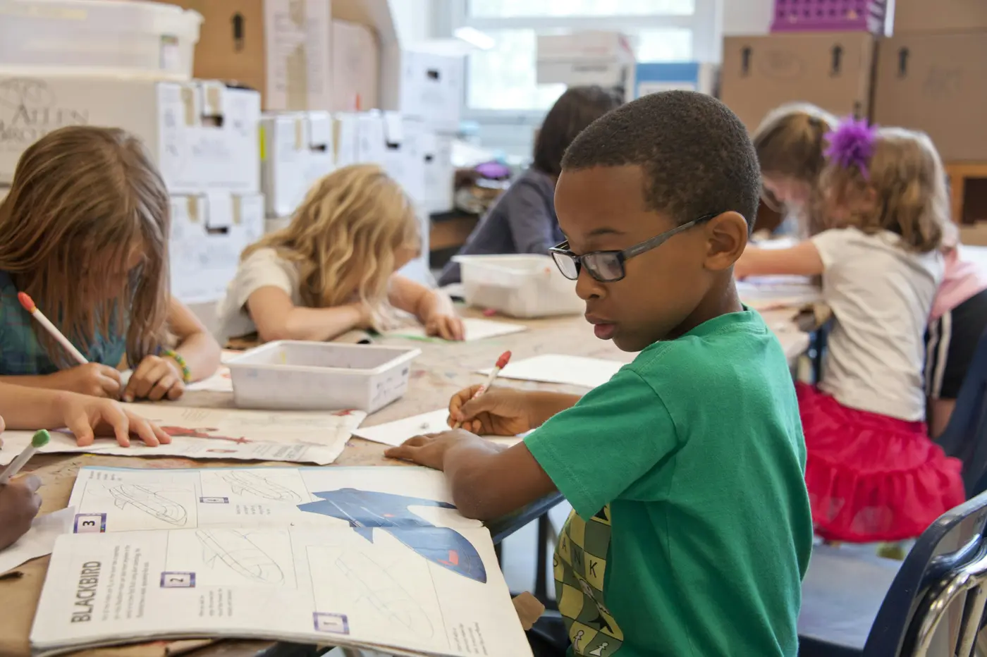 A tutor and a student working together at a classroom table.